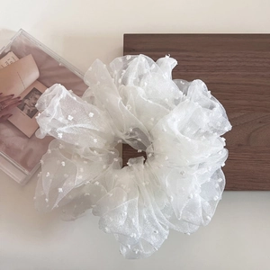 Detail of oversized white mesh scrunchie with fluffy polka dots and soft pleated texture