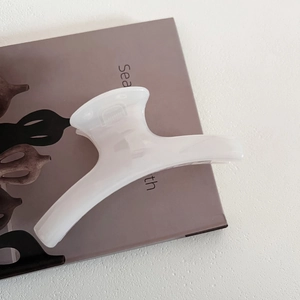 Close-up of a translucent creamy white resin hair claw clip on a minimalist background
