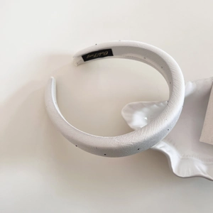 Macro detail of white satin headband with silver rhinestones and interior brand label