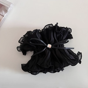 Close-up of black ruffled scrunchie with silk bow and faceted rhinestone center