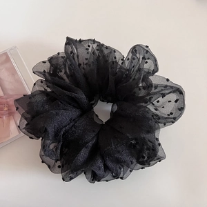 Detailed texture of black organza scrunchie with polka dots and fluffy mesh folds