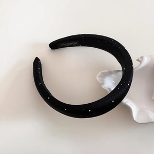 Detail of black satin headband with shimmering silver sequins and inner gold label