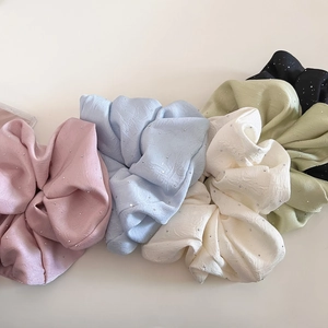 Detailansicht funkelnder Satin-Haargummis mit Strasssteinen in fünf sanften Pastellfarben