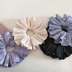 Detail von vier plissierten Perlen-Haargummis in den Farben Violett, Weiß, Blau und Schwarz