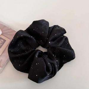 Detailaufnahme von schwarzem Satin-Haargummi mit schimmernden silbernen Glitzer-Akzenten