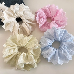 Détail de quatre chouchous en dentelle blanche, rose, jaune et bleue avec broderie