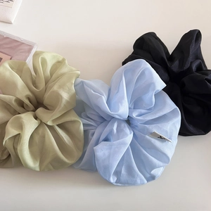 Détail de trois chouchous en organza scintillant dans les tons or, bleu et noir chic