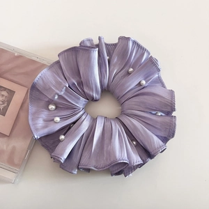 Detail eines lila Satin-Haargummis mit Faltenstruktur und eleganten weißen Perlen für Haar