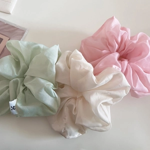 Vue détaillée de chouchous en organza vert pastel, blanc et rose avec un éclat perlé