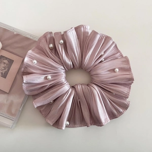 Detailaufnahme des rosa Falten-Satin-Haargummis mit weißen Perlen auf hellem Hintergrund