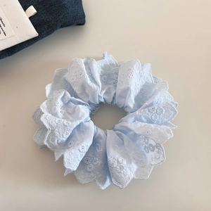 Détail d'un chouchou en dentelle bleu clair à double couche avec broderie florale blanche