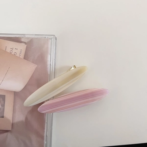 Close-up of cream and pink marble oval acetate hair clips with golden metal bases