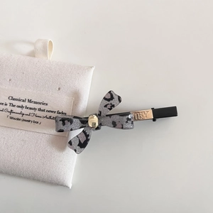 Detailansicht der grauen Haarspange mit Leopardenmuster-Schleife und goldener Plakette