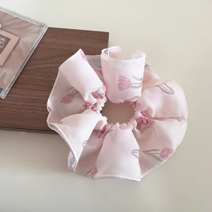 Dettaglio di un elastico per capelli in chiffon rosa con stampa floreale di tulipani