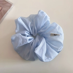 Détail d'un chouchou en tulle bleu clair avec texture scintillante et petite étiquette