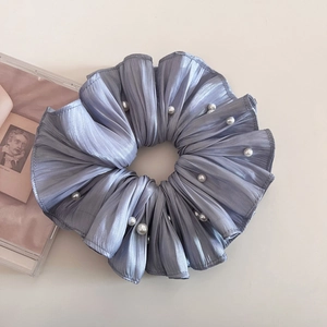 Detail eines silbernen Faltenhaargummis mit eleganten Perlenverzierungen