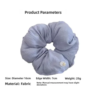 Detailed view of lilac scrunchie with button detail and soft cotton fabric texture