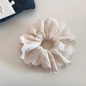 Détail d'un chouchou en dentelle blanche double couche avec broderie et volants