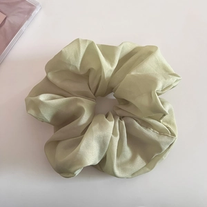 Gros plan sur chouchou en organza vert clair pailleté avec texture plissée douce