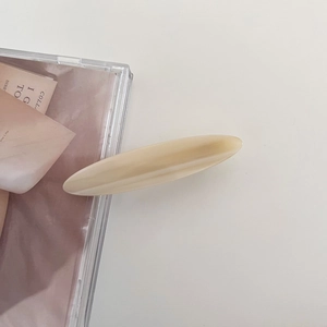 Macro view of the creamy yellow oval acetate hair clip with smooth resin finish