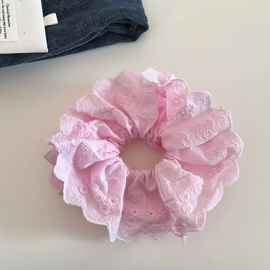 Détail d'un chouchou en dentelle rose double couche avec broderie florale
