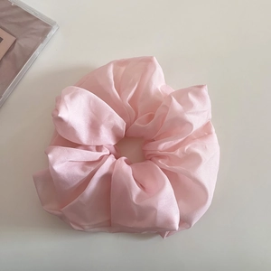 Gros plan sur le chouchou en tulle rose avec texture satinée et plis élégants