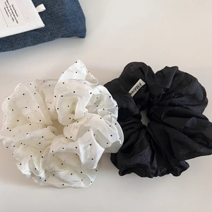Close-up of black and white polka dot mesh scrunchies set with a woven label detail