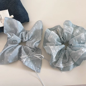 Lichtblauwe geruite haarelastiekjes met wit kant en strikje op denim achtergrond