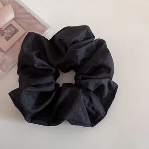 Gros plan sur un chouchou noir oversize avec tissu scintillant et texture plissée douce