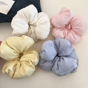 Pastel cotton scrunchies set in cream, pink, and blue with decorative gold buttons