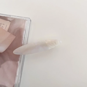 Close-up of cream marble oval hair clip on a minimalist aesthetic background