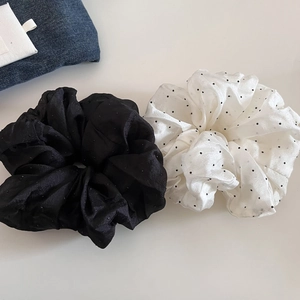 Flat lay of mesh scrunchies in solid black and white polka dot patterns for hair styling