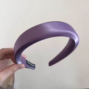 Détail du serre-tête en satin violet montrant l'étiquette tissée Hand Made à l'intérieur
