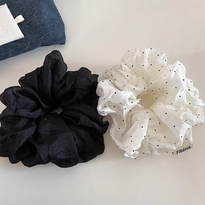 Close-up of mesh scrunchies in solid black and white polka dot with delicate textures