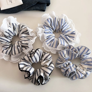 Detailed view of blue and white striped scrunchies with elegant lace edges and fabric texture
