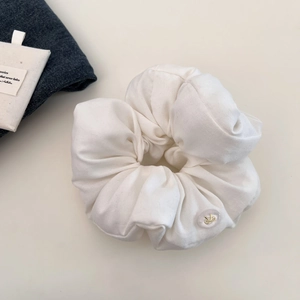 Detail of white cotton scrunchie with transparent button and golden bow embellishment