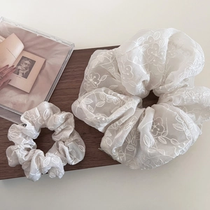 Gros plan de chouchous en organza blanc avec broderie florale sur livre vintage