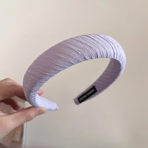 Détail d'un serre-tête rembourré lavande avec tissu plissé et étiquette fait main