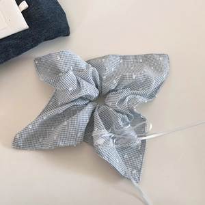 Detail van een lichtblauw geblokte scrunchie met witte kant en lange zijden linten
