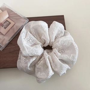 Grand chouchou élégant en dentelle blanche brodée avec fleurs sur fond en bois rustique