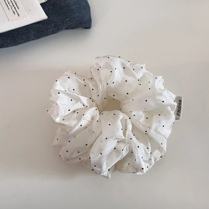 Elegant white mesh scrunchie with black polka dots and a minimalist fabric brand label