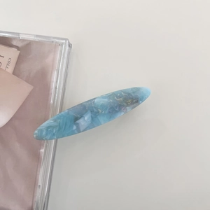 Detail of blue marble acetate hair clip with gold leaf texture and oval shape design