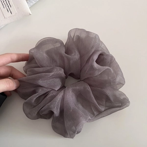 Gros plan sur un chouchou en tulle gris-violet nacré avec texture en organza superposée