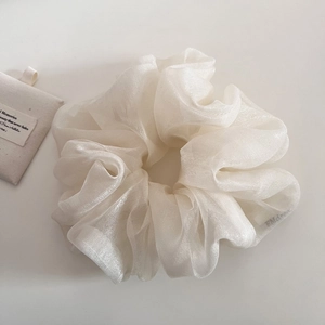 Détail d'un chouchou en organza blanc avec éclat perlé et texture plissée