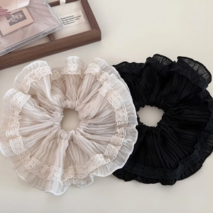 Detailed view of beige and black ruffled chiffon scrunchies with delicate lace edges