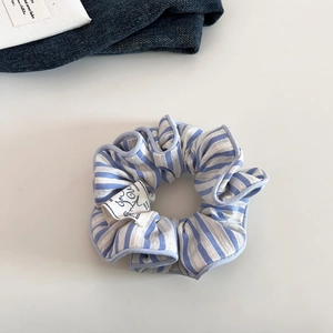 Close-up of blue and white striped fabric scrunchie with handmade tag and lace edging