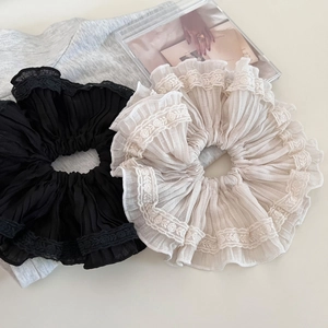 Elegant beige and black pleated lace scrunchies on a soft textured background