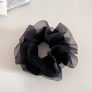 Détail d'un chouchou en organza noir montrant la texture plissée et le volume du voile