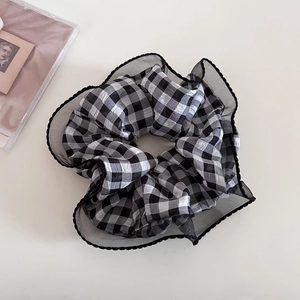 Dettaglio di elastico scozzese con bordi pieghettati in organza nera su sfondo bianco