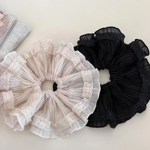 Macro shot of pleated lace scrunchies in black and beige with delicate embroidery detail
